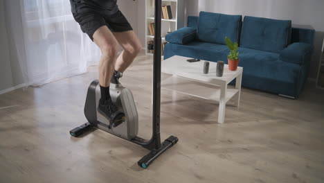 male-legs-on-stationary-bike-in-living-room-adult-man-is-training-alone-for-health-and-good-physical-condition-details-shot-of-body